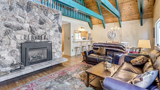 A spacious living area with a stone fireplace, leather sofas, and a wooden ceiling. - Multi-Family Cabin in Great Location! - Home #183 by Bear Valley Vacation Rentals (Arnold)