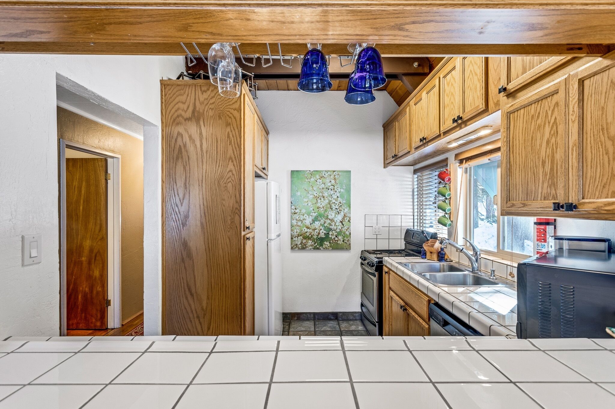 A kitchen with wooden cabinets, a stove, a sink, and a window with blinds.