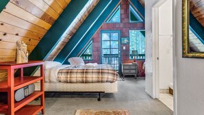 A bedroom with a sloped ceiling, a bed, a nightstand, and a dresser. - Multi-Family Cabin in Great Location! - Home #183 by Bear Valley Vacation Rentals (Arnold)