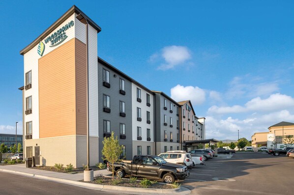 A hotel with a modern design, featuring a prominent sign, multiple floors, and a parking lot with various vehicles.