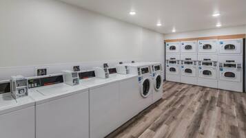 Een moderne wasserette met meerdere wasmachines en drogers, een digitaal bedieningspaneel en een houten vloer.