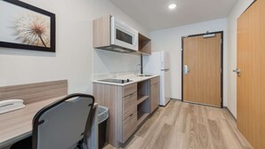 A compact kitchenette with a microwave, sink, and storage cabinets.