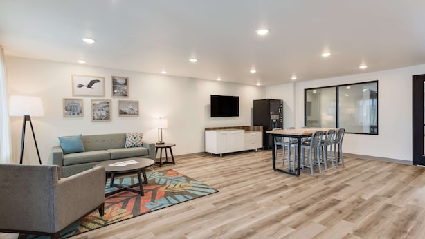 A modern living room with a sofa, armchair, coffee table, and a dining area with chairs and a table.