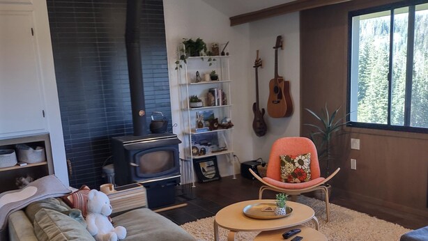 A living room with a sofa, a coffee table, a fireplace, a guitar, and a bookshelf. - Stunning! Enjoy The Best Views In All Of Bear Valley When You Stay At This Unique Property 3 Bedroom Apts by RedAwning (Arnold)