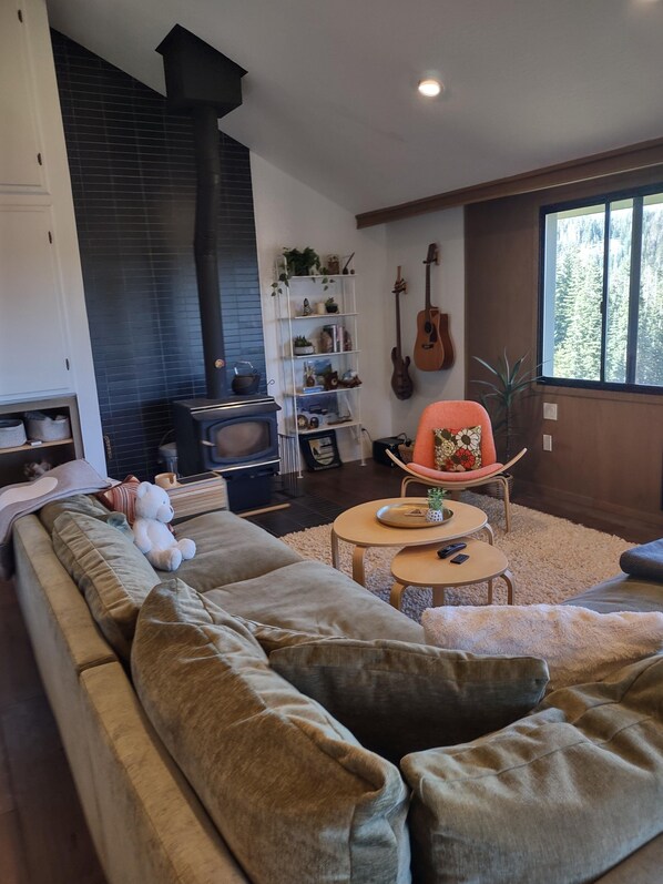 A living room with a sofa, a coffee table, a fireplace, a guitar, and a bookshelf.