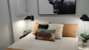 A bedroom with a bed, pillows, a wall-mounted artwork of a bull, bedside lamps, and a potted plant. - Stunning! Enjoy The Best Views In All Of Bear Valley When You Stay At This Unique Property 3 Bedroom Apts by RedAwning (Arnold)