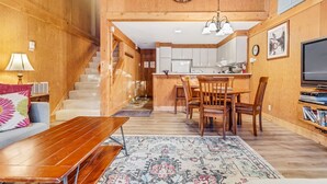 A wooden interior with a dining area, kitchen, and a staircase leading to upper floors. - Modern & Sleek Condo - Creekside #110 by Bear Valley Vacation Rentals (Arnold)