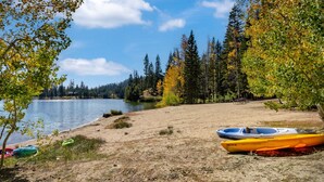 A lakeside beach with kayaks and a picnic table. - Modern & Sleek Condo - Creekside #110 by Bear Valley Vacation Rentals (Arnold)