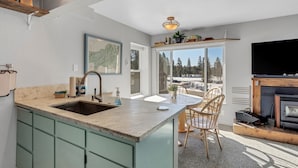 A modern kitchen with a large island, a dining area with a view, and a fireplace. - Great Location Corner Condo - Tamarack #10 Pets OK - 2 Bedroom Condo by Bear Valley Vacation Rentals (Arnold)