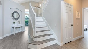 Un interior moderno con una escalera, una consola blanca y una puerta que da a otra habitación.