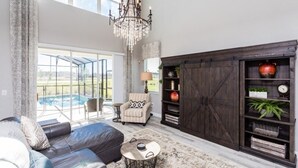 A spacious living room with a large sectional sofa, a chandelier, a fireplace, and a view of a swimming pool. - 5 bedroom home is ideal for an elegant vacation 5 Villa by RedAwning (Kissimmee)
