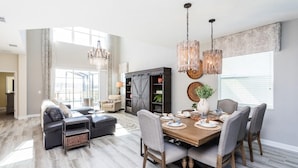 A spacious living room with a large dining table, comfortable seating, and a chandelier. - 5 bedroom home is ideal for an elegant vacation 5 Villa by RedAwning (Kissimmee)