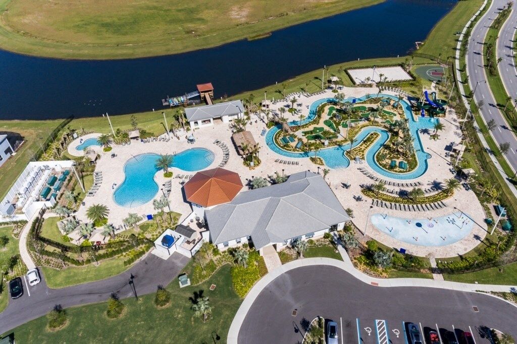 An aerial view of a resort with multiple swimming pools, a large building, and a road nearby.
