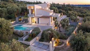 A modern villa with a swimming pool, surrounded by lush vegetation and hills. - Stefania - Two Bedroom Villa, Sleeps 4 (Acharavi)
