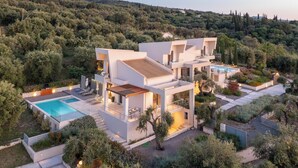 A modern villa with a swimming pool, multiple balconies, and lush surrounding vegetation. - Stefania - Two Bedroom Villa, Sleeps 4 (Acharavi)