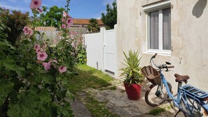 A bicycle parked next to a building with a window and a potted plant. - Charming house la Rochelle easter vacations (La Rochelle)