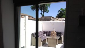 A view through a glass door into a patio area with a sofa, wicker furniture, and a birdcage. - Charming house la Rochelle easter vacations (La Rochelle)