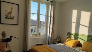 A bedroom with a bed, a window, a Buddha statue, and a framed picture of a giraffe. - Charming house la Rochelle easter vacations (La Rochelle)