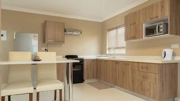 A modern kitchen with wooden cabinets, a built-in microwave, and a white countertop.