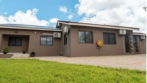 A modern building with a flat roof, multiple windows, and air conditioning units.