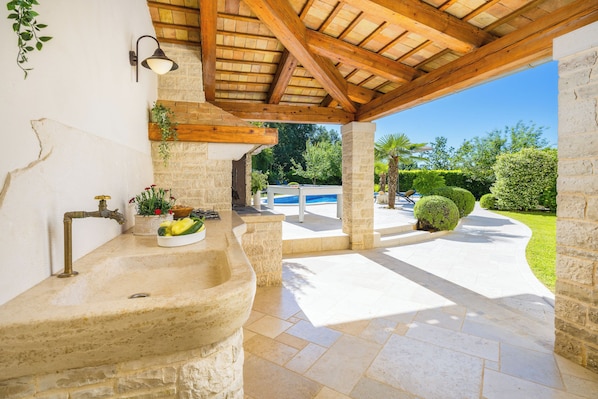 A stone sink with a faucet, a potted plant, and a bowl of fruit.
