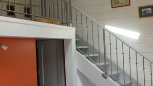 A hotel room with a bed, a nightstand, a lamp, a staircase, and a door leading to another room.