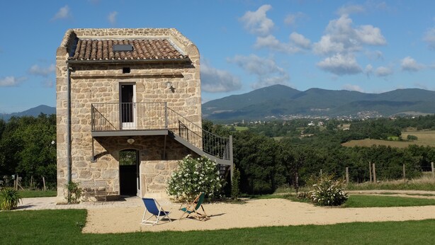 A stone building with a balcony, a door, and a small window.