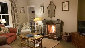 Una sala de estar acogedora con chimenea, un sofá, un sillón y un televisor.