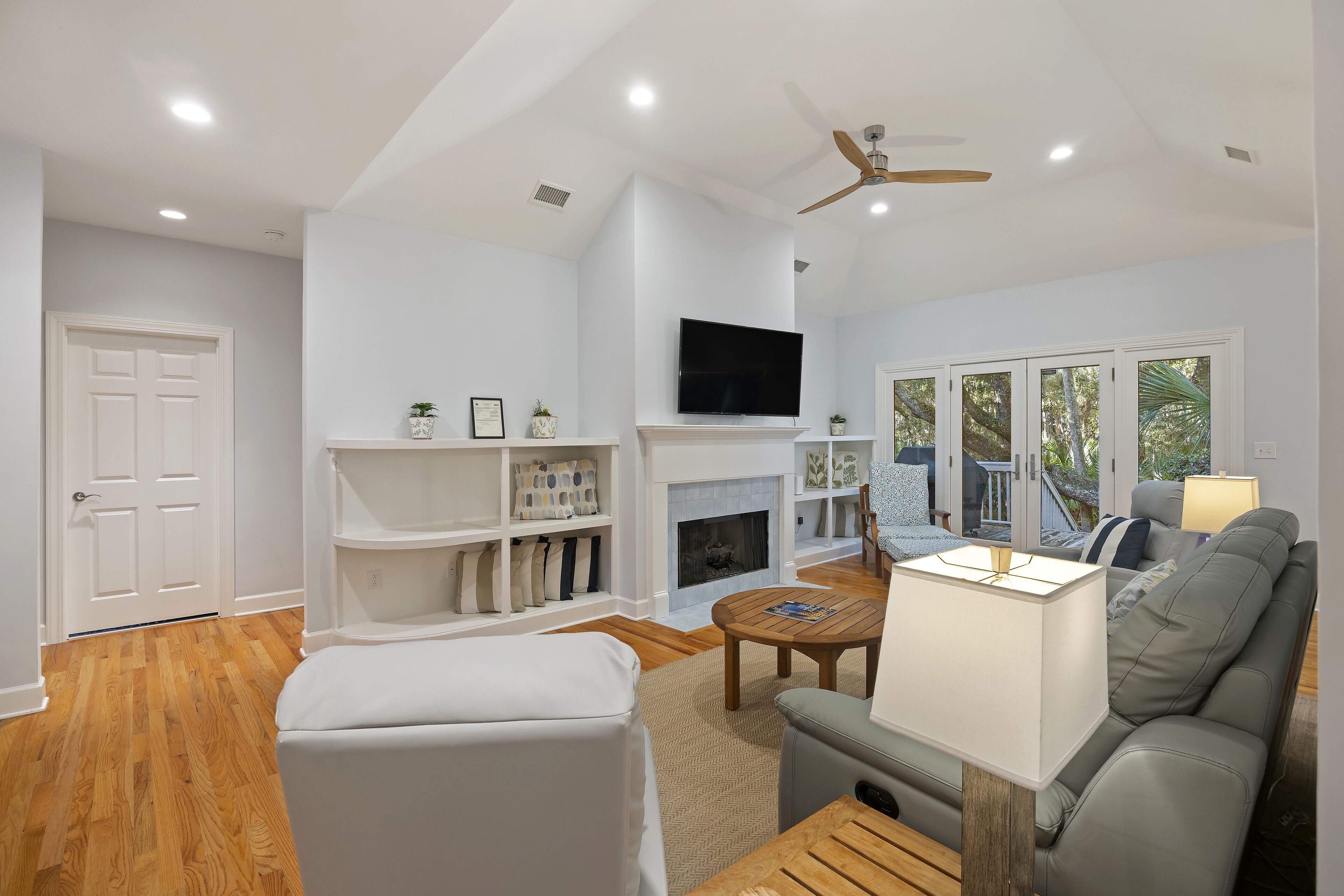 Un salon moderne avec une cheminée, un téléviseur et un ventilateur de plafond.