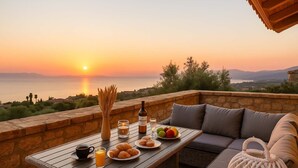 Ein Sonnenuntergangsblick von einer Terrasse mit einem Frühstückstisch, der Croissants, Obst und Getränke umfasst.