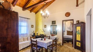 Um quarto acolhedor com teto de madeira, uma mesa de jantar com cadeiras, um sofá, uma cama e um armário.
