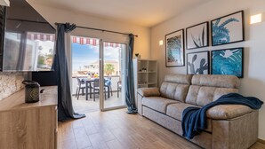 A living room with a beige sofa, a wooden coffee table, and a sliding glass door leading to an outdoor patio. - Bungalow apartment with private pool & ocean views (Adeje)