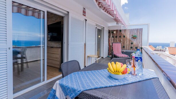 A balcony with a table set for dining, a bowl of fruit, and a bottle of water. - Bungalow apartment with private pool & ocean views (Adeje)