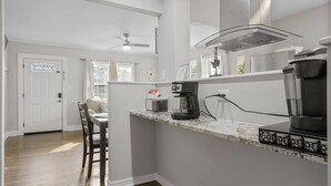 Une cuisine dotée d’un plan de travail en marbre, d’une machine à café et d’un ventilateur de plafond.