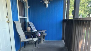 Puinen terassi, jossa on sininen seinä, lasiovi sekä pöytä ja tuolit.