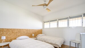 A bedroom with two beds, a ceiling fan, a window with blinds, and a small table with a lamp. - Bright Apt With Balcony And Sea View (Antibes)