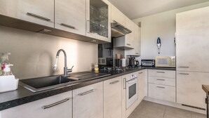 A modern kitchen with a stainless steel sink, a built-in oven, and a microwave. - Bright Apt With Balcony And Sea View (Antibes)