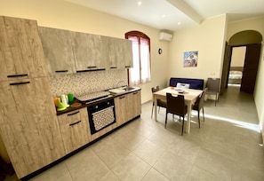 A modern kitchen with wooden cabinets, a tiled backsplash, and a dining area with a table and chairs.