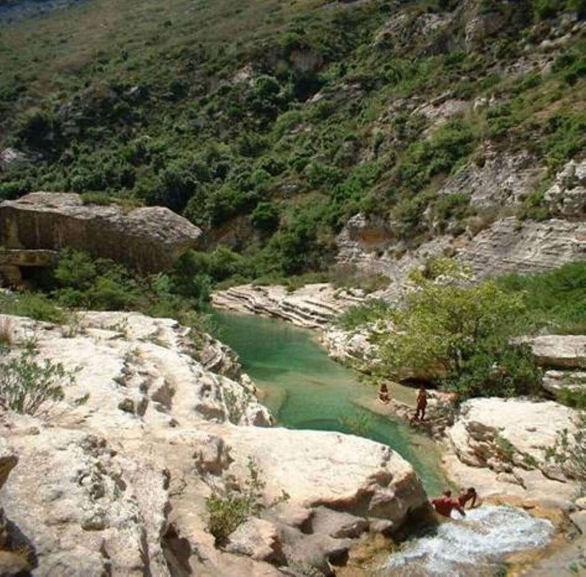A natural landscape with a rocky terrain and a clear water body.
