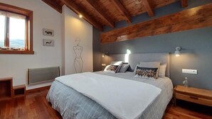 A bedroom with a large bed, wooden ceiling beams, a radiator, and a window with curtains. - Infinity mountain view (Angoustrine-Villeneuve-des-Escaldes)