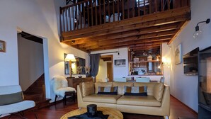 A cozy living room with a high wooden ceiling, a leather sofa, a round wooden coffee table, and a black and white cowhide rug. - Infinity mountain view (Angoustrine-Villeneuve-des-Escaldes)
