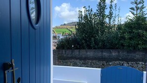 A blue door with a view of a garden and a blue gate leading to a paved area. - Casa do Porto, relax with this stunning sea view (Porto Formoso)