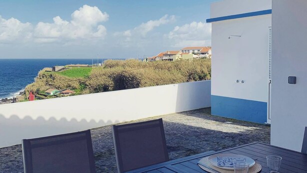A table set for two with a view of the ocean and houses in the background. - Casa do Porto, relax with this stunning sea view (Porto Formoso)