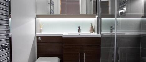 Ein modernes Badezimmer mit Toilette, Holzwaschbecken, Spiegel und Duschbereich.