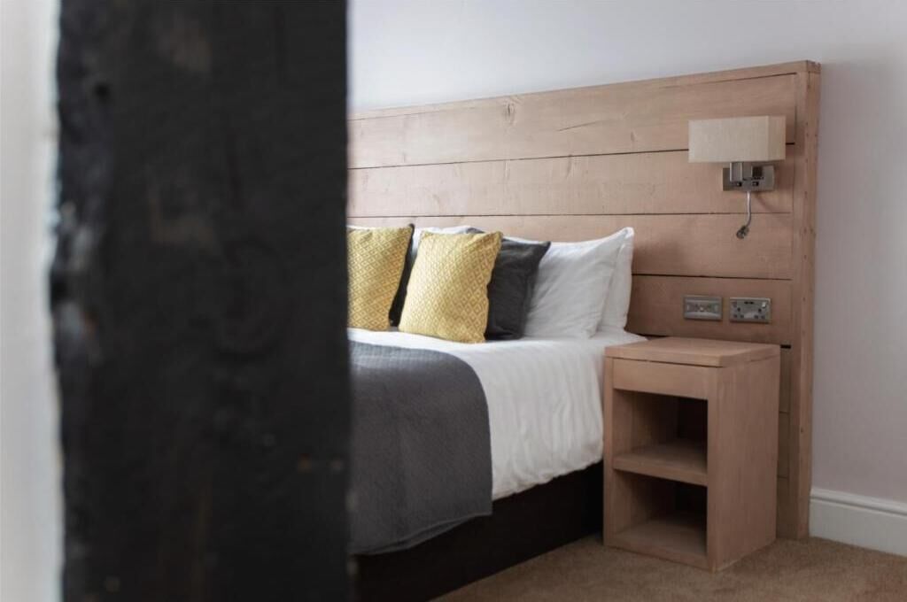 Een slaapkamer met een houten hoofdbord, een nachtkastje en een bedtafel.