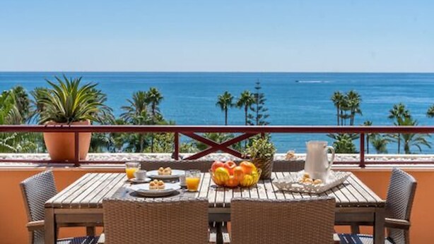 Ein Balkon mit Frühstückstisch, mit Blick auf den Ozean.