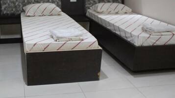 Habitación de hotel con dos camas individuales, cada una con cabecero oscuro y ropa de cama blanca con rayas rojas.