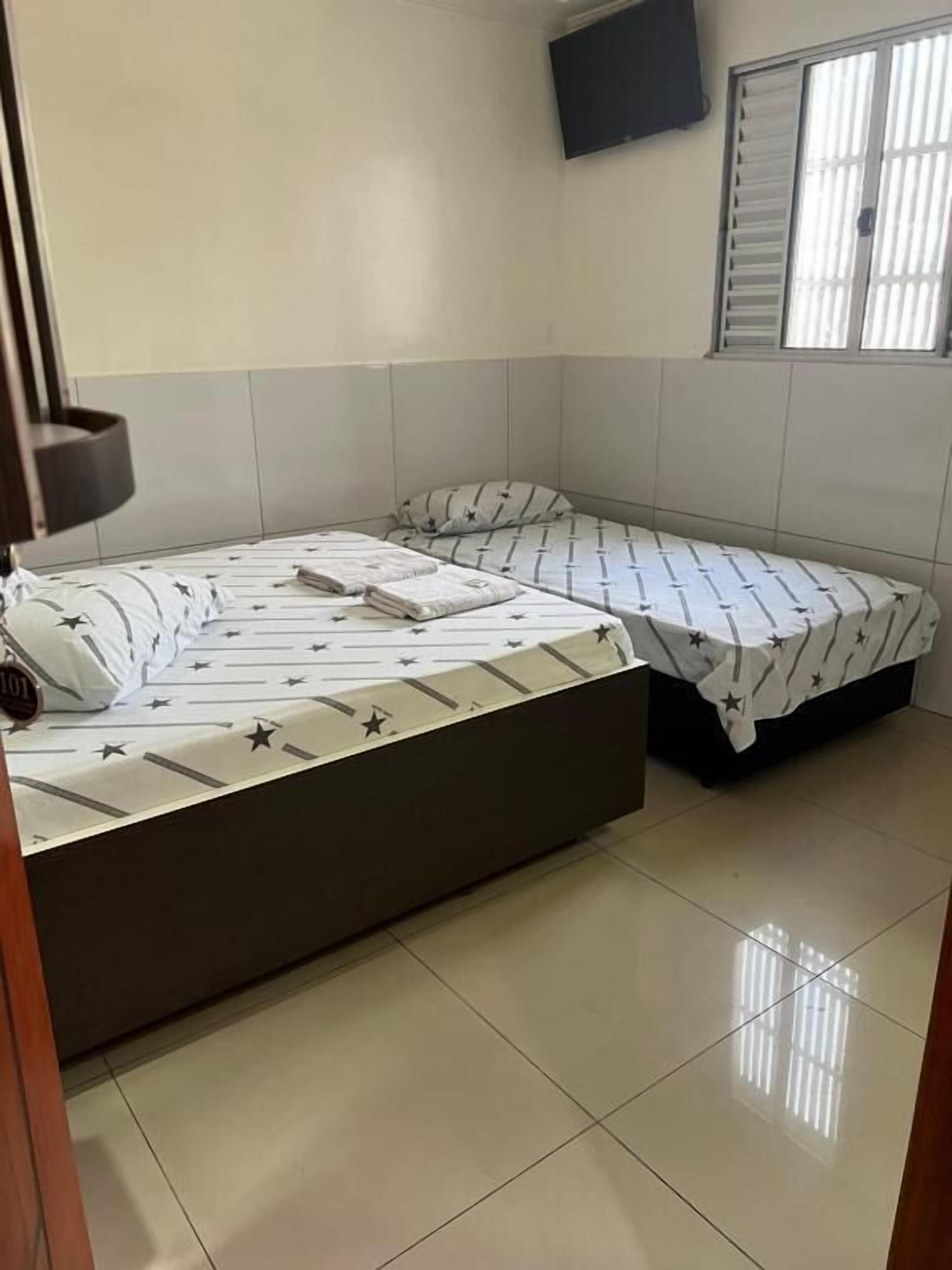 A room with two beds, one larger and one smaller, both with star-patterned bedding.
