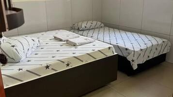 A room with two beds, one larger and one smaller, both with star-patterned bedding.