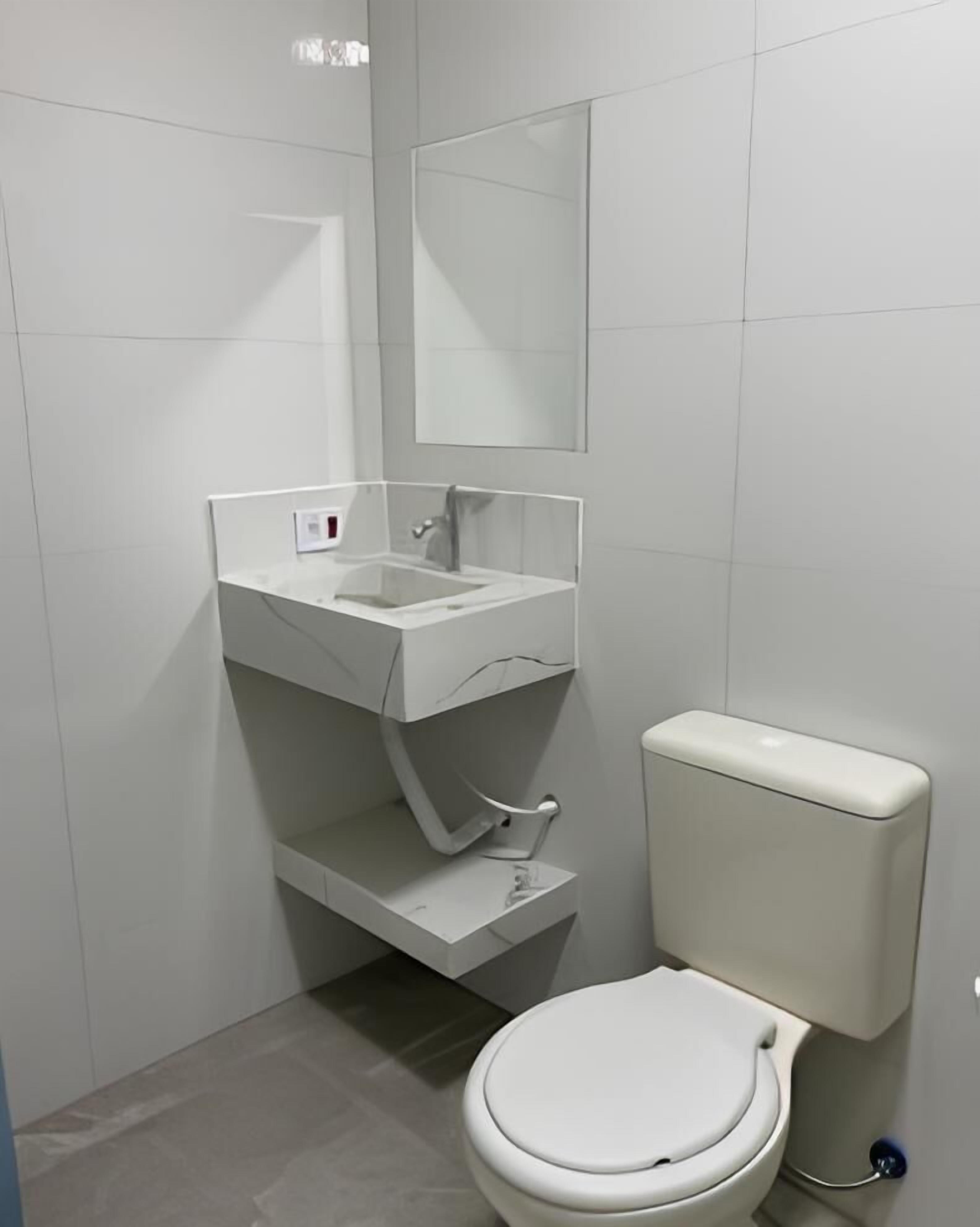 A modern bathroom with a toilet, a sink, and a mirror.